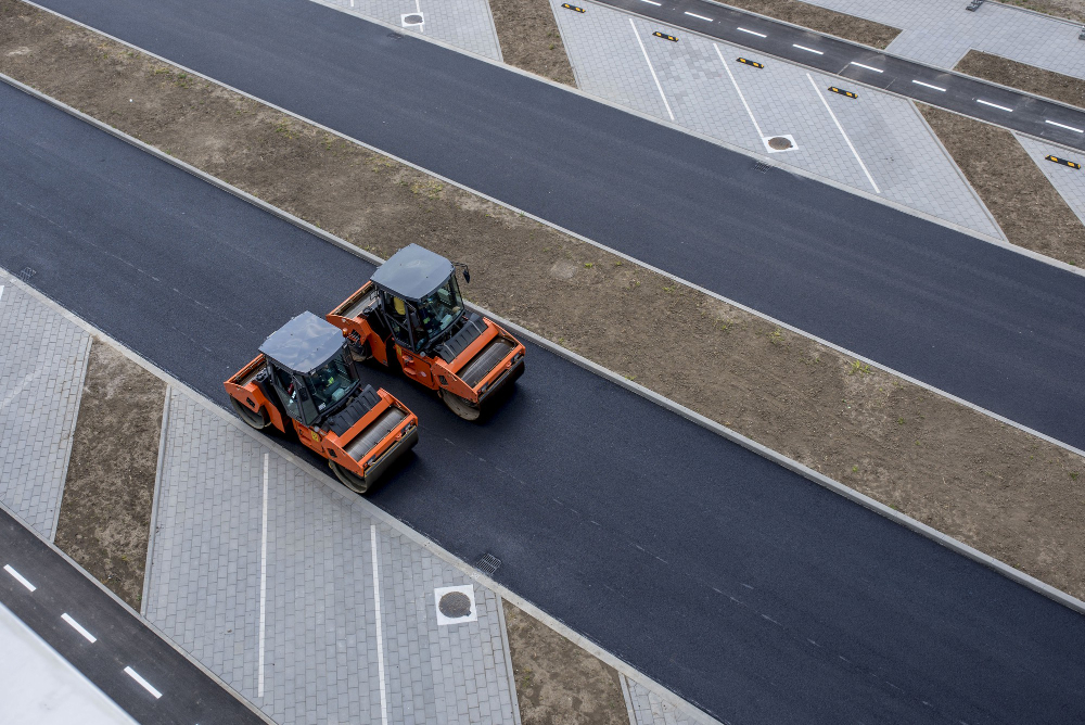 Free photo aerial view of orange vibratory asphalt roller compactor on a new pavement